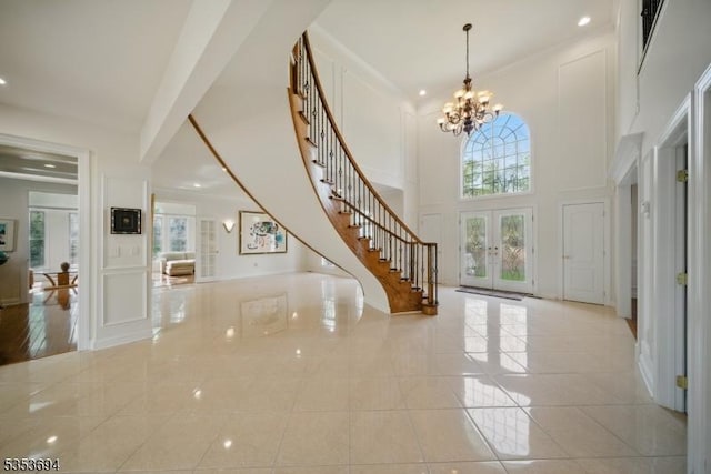 tiled entrance foyer with a towering ceiling, stairway, recessed lighting, a chandelier, and french doors