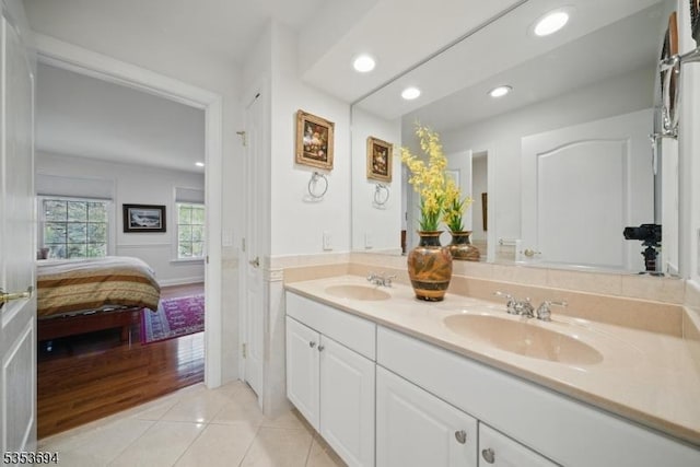 ensuite bathroom with ensuite bathroom, a sink, tile patterned floors, and double vanity
