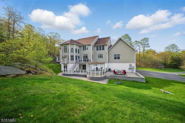 back of property with a lawn, a patio, and stairway