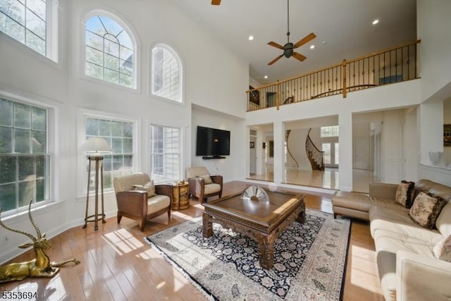 living room featuring high vaulted ceiling, light wood-style flooring, a ceiling fan, recessed lighting, and stairway