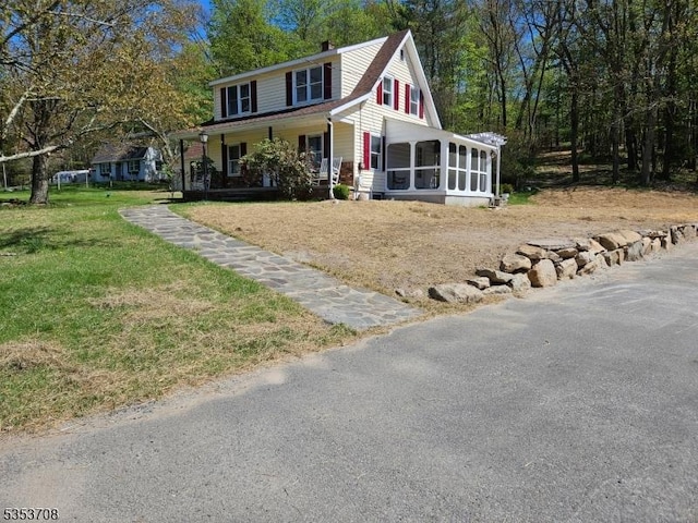 farmhouse-style home featuring a chimney, a sunroom, and a front lawn