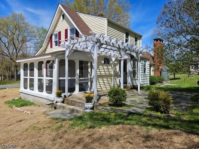 back of house with a pergola, a chimney, and a sunroom
