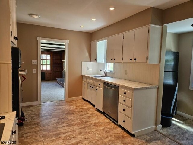 kitchen with decorative backsplash, baseboards, light countertops, a sink, and dishwasher