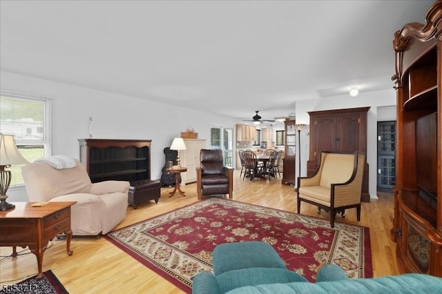 living room with plenty of natural light, a ceiling fan, and light wood-style floors