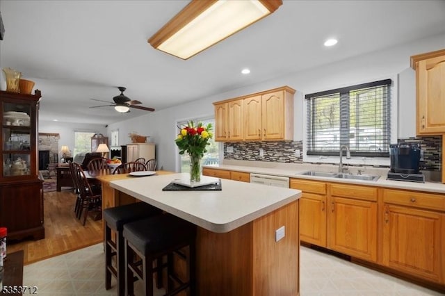 kitchen featuring a sink, light countertops, a kitchen island, decorative backsplash, and a breakfast bar