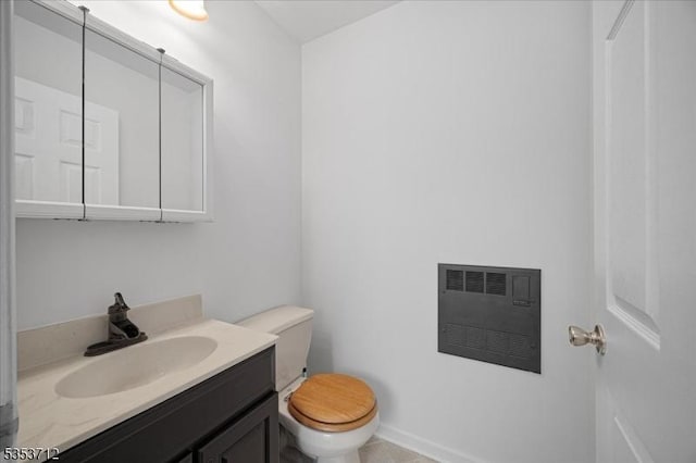 half bath featuring toilet, heating unit, vanity, and baseboards