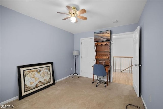 carpeted office space with ceiling fan and baseboards