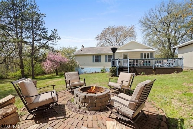 rear view of house featuring a fire pit, a wooden deck, and a yard