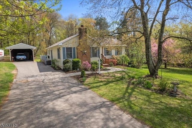 view of front of home featuring a carport, a front lawn, asphalt driveway, and a chimney