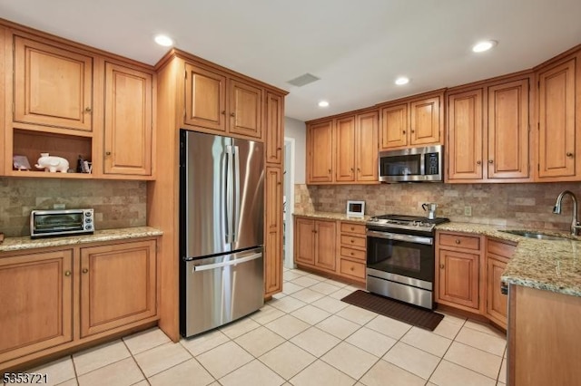 kitchen with appliances with stainless steel finishes, decorative backsplash, and a sink