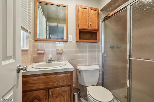 full bathroom featuring vanity, toilet, tile walls, and a shower stall