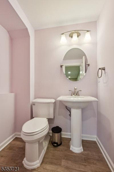 bathroom with toilet, baseboards, and wood finished floors