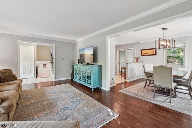 living room with baseboards, a chandelier, crown molding, and wood finished floors