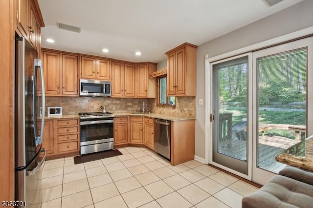 kitchen featuring light stone countertops, visible vents, a sink, backsplash, and appliances with stainless steel finishes