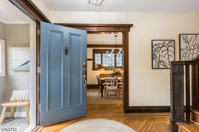entrance foyer featuring baseboards, wood finished floors, and a chandelier