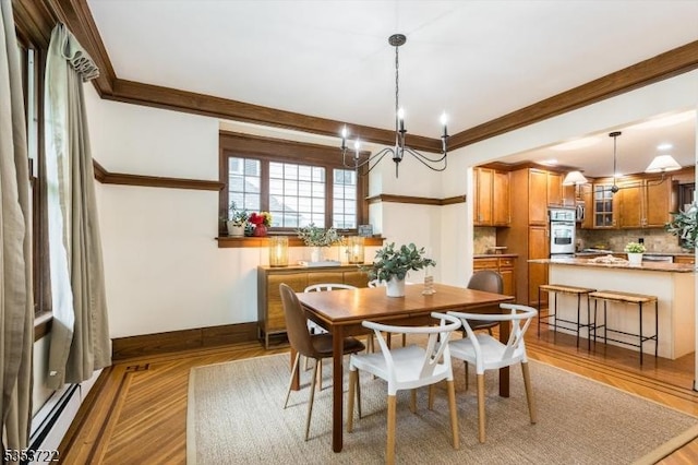 dining room featuring ornamental molding, baseboards, wood finished floors, a chandelier, and a baseboard heating unit