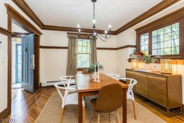 dining area featuring ornamental molding, healthy amount of natural light, a chandelier, baseboard heating, and light wood-type flooring