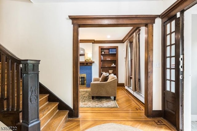 corridor featuring stairs, wood finished floors, baseboard heating, baseboards, and ornamental molding