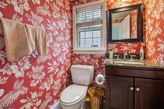 bathroom with wallpapered walls, toilet, and vanity