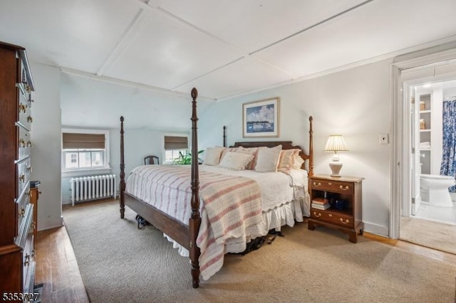 bedroom with radiator, wood finished floors, and ensuite bathroom
