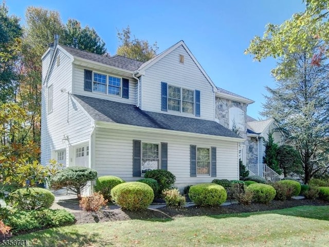 view of front facade featuring a front lawn, a shingled roof, and a garage