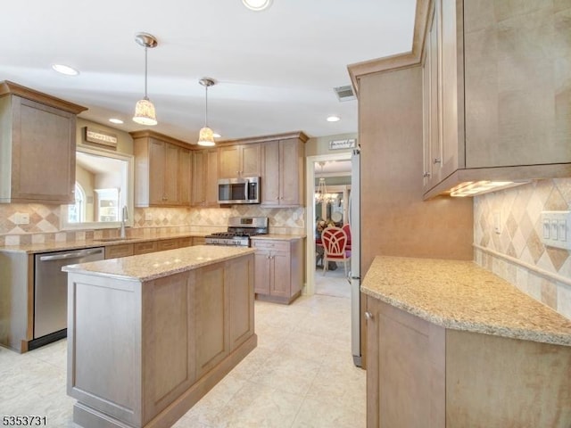 kitchen featuring light stone counters, decorative backsplash, appliances with stainless steel finishes, a sink, and a center island