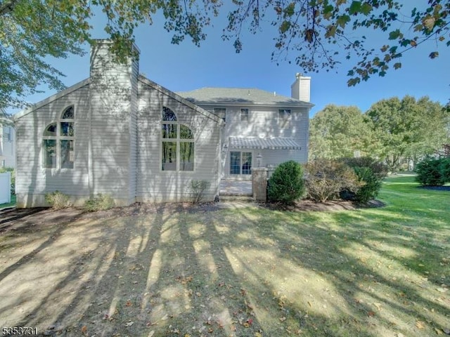 rear view of house with a yard and a chimney