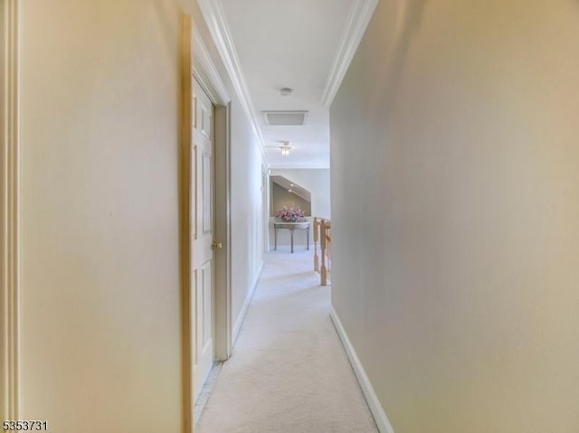 hallway with crown molding, light colored carpet, visible vents, baseboards, and attic access