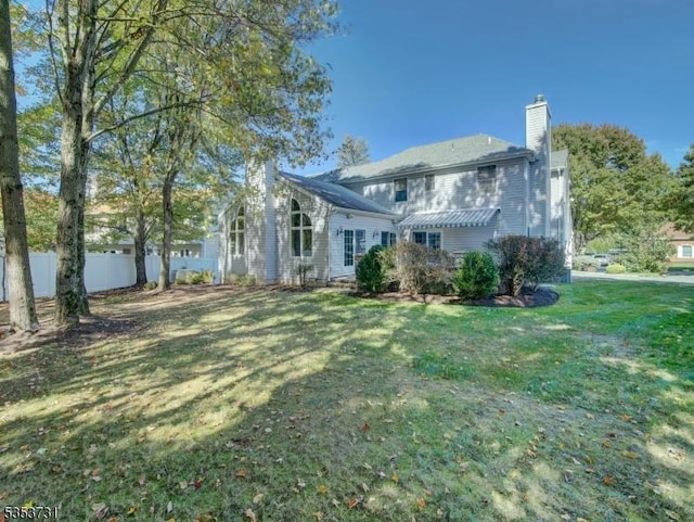 view of front facade with a chimney, fence, and a front lawn