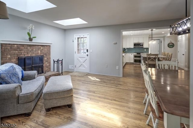 living area with a skylight, wood finished floors, and a fireplace