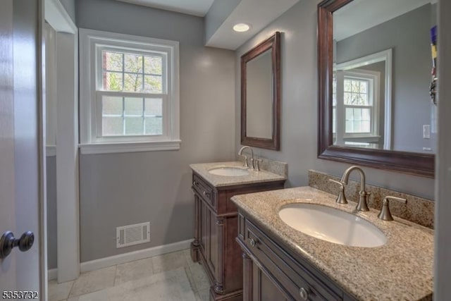 bathroom with two vanities, visible vents, baseboards, and a sink