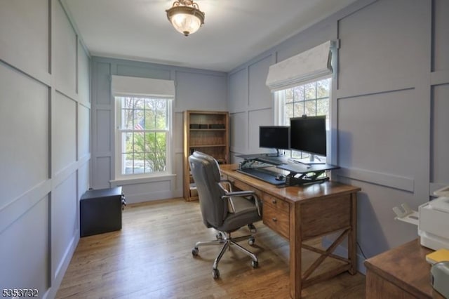 office area featuring a wealth of natural light, light wood finished floors, and a decorative wall