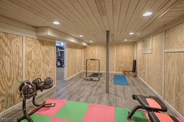exercise area featuring wooden walls, wood finished floors, and recessed lighting