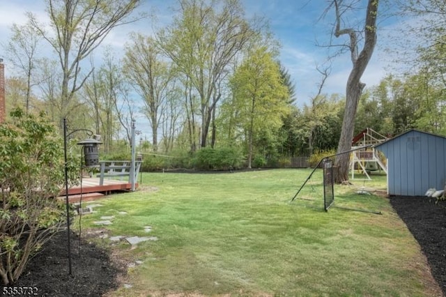 view of yard featuring an outdoor structure, a wooden deck, and a storage shed