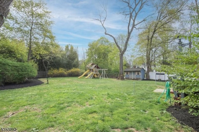 view of yard with an outdoor structure, a fenced backyard, a playground, and a storage shed