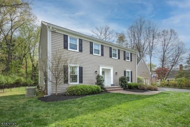 colonial home with a front lawn, fence, and central AC unit