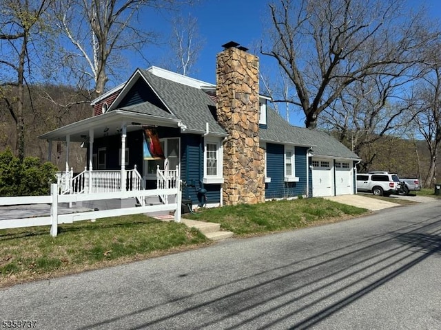 view of front facade featuring a chimney, a porch, driveway, roof with shingles, and an attached garage