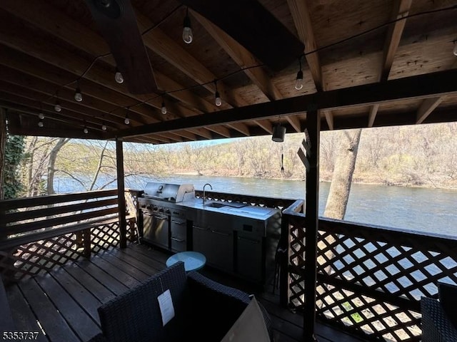 deck with a water view, a view of trees, and a sink
