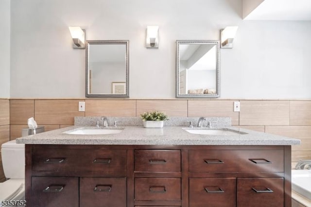 full bath with double vanity, toilet, wainscoting, and a sink