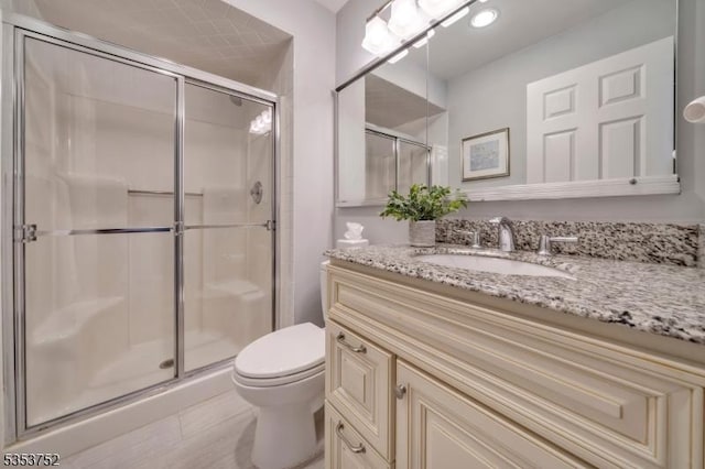 bathroom with toilet, a shower stall, and vanity