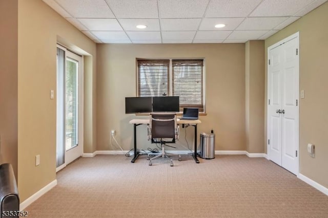 carpeted home office featuring baseboards, a drop ceiling, and plenty of natural light