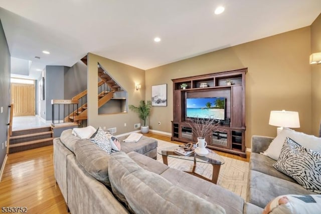 living area with baseboards, light wood-style flooring, stairs, and recessed lighting