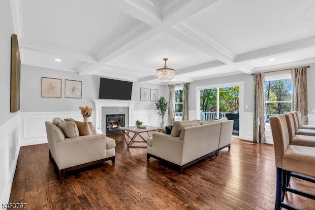 living area featuring coffered ceiling, a glass covered fireplace, and a decorative wall