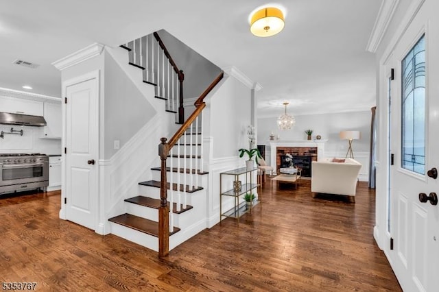 staircase with visible vents, ornamental molding, and wood finished floors