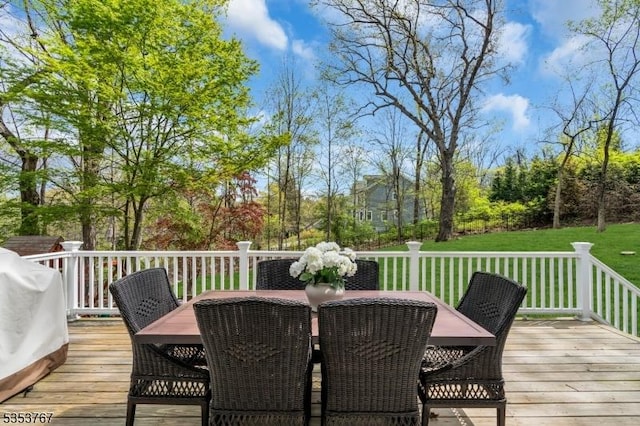 wooden deck featuring a lawn, outdoor dining space, and a grill