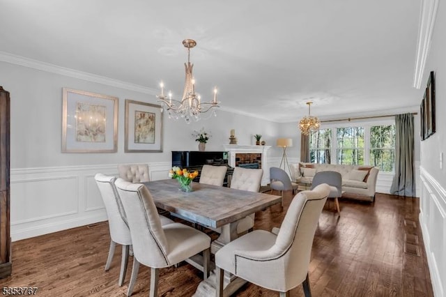 dining space with an inviting chandelier, ornamental molding, wood finished floors, and a wainscoted wall