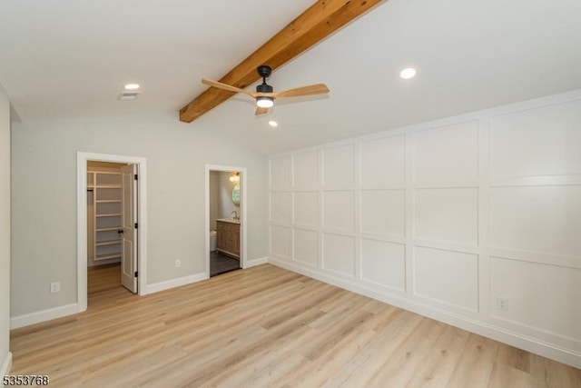 unfurnished bedroom featuring visible vents, vaulted ceiling with beams, a spacious closet, and light wood-type flooring