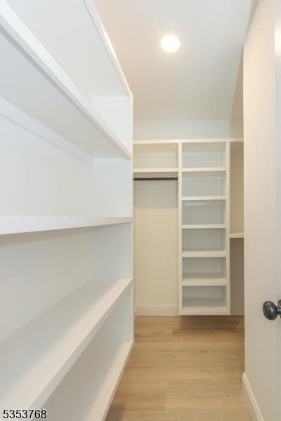 walk in closet with light wood-style floors