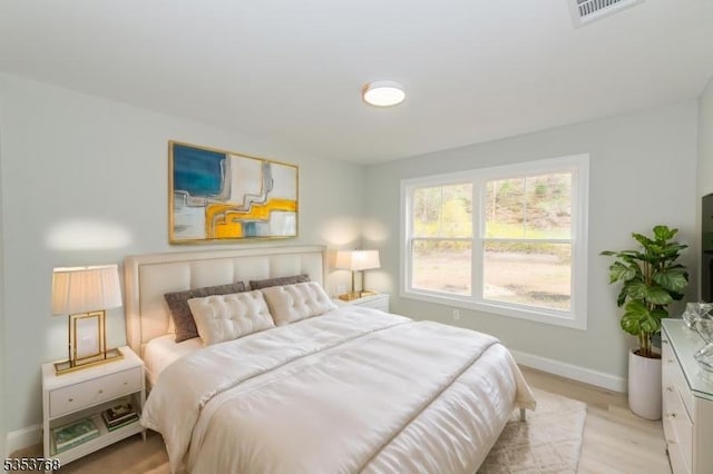 bedroom featuring baseboards, visible vents, and light wood finished floors
