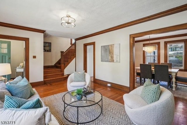 living room with ornamental molding, stairway, baseboards, wood finished floors, and a chandelier